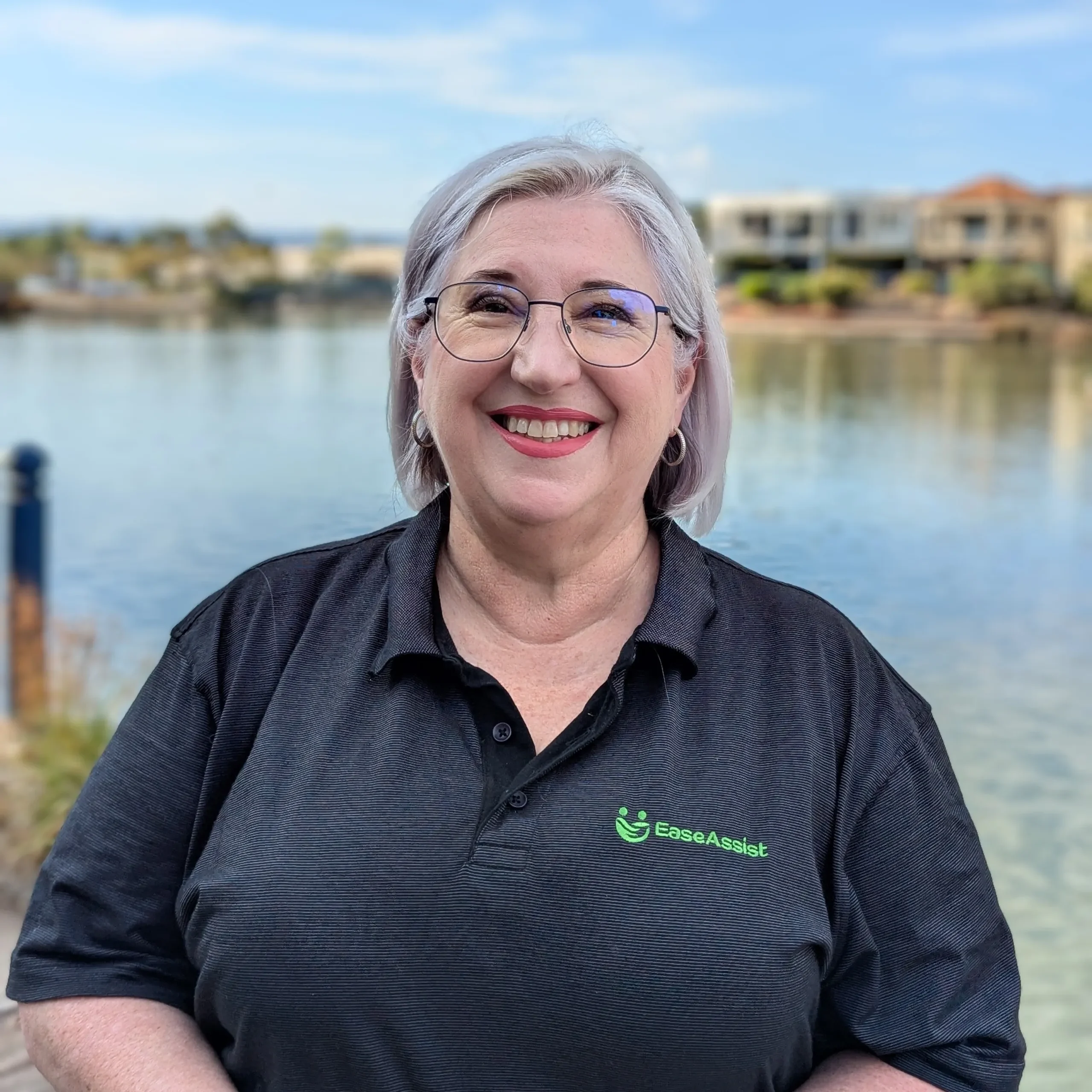 A woman standing in front of water and buildings.