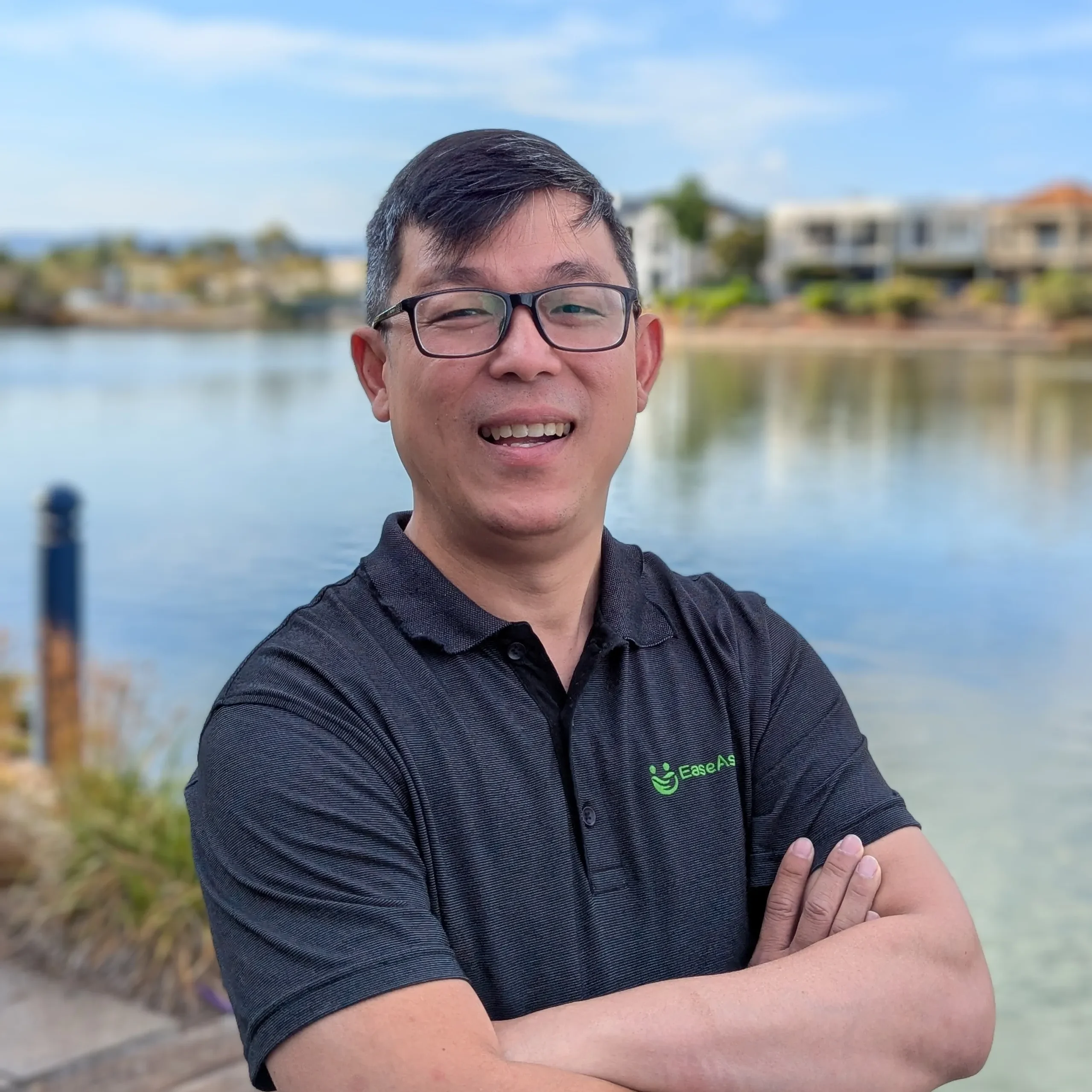 A man standing in front of water with his arms crossed.
